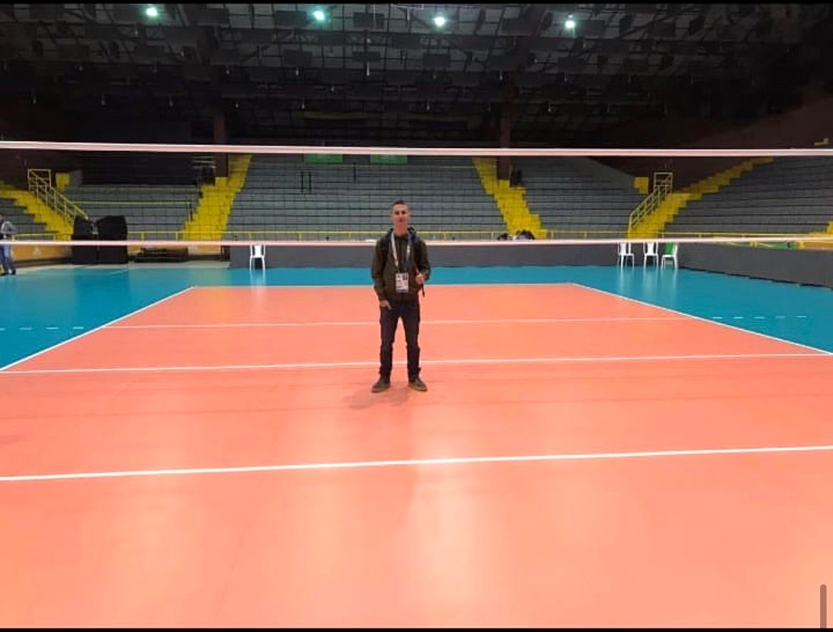 Luis Zuluaga standing courtside in an empty championship arena